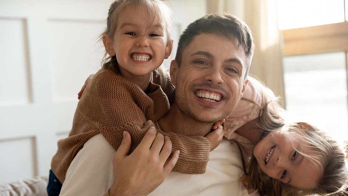 father and daughters smiling