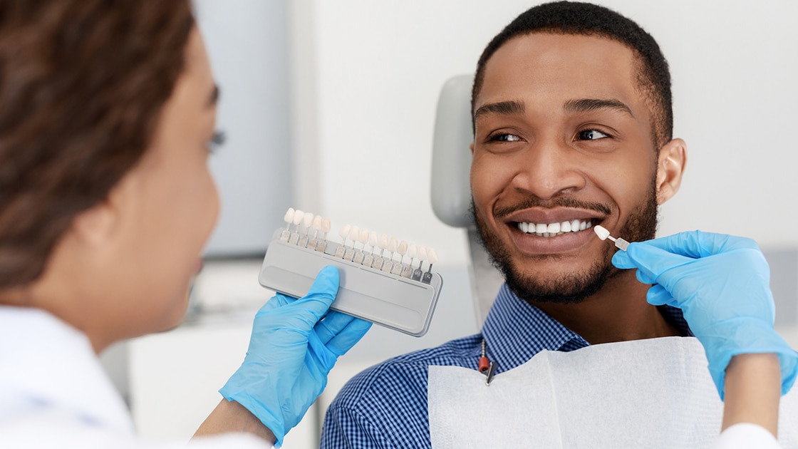 dentist holding up tooth shade guide to patient