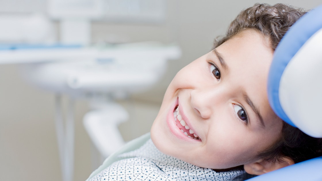 young child in dentist chair smiling
