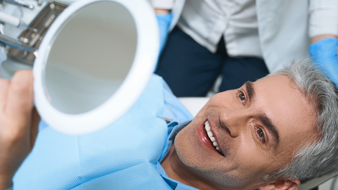 man in patient chair looking in mirror